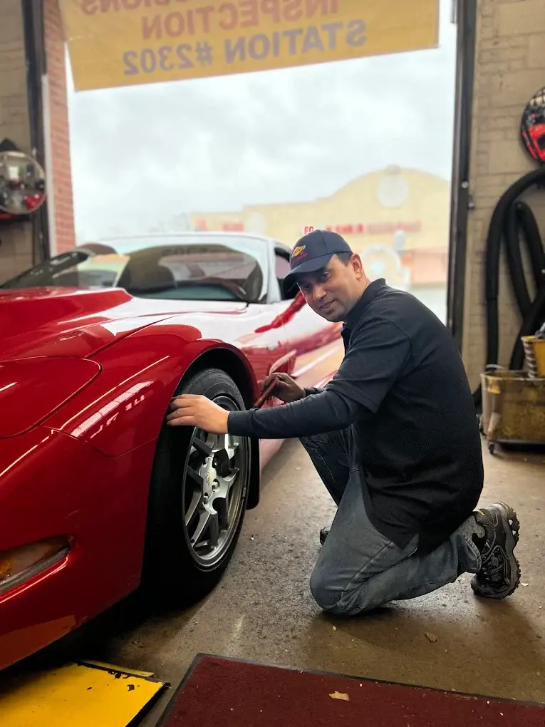 Technician checking a car under the emissions inspection station sign at Rolling Road Sunoco in Springfield after a failed emissions test in Virginia